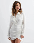Modèle portant une Mini-Robe Portefeuille Chemise Courte Blanc Asymétrique - Élégance Chic et Structurée. Robe portefeuille blanche, col structuré et manches longues, idéale pour un look sophistiqué.
