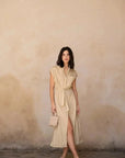 Femme marchant en robe chemise femme beige midi ceinturée, affichant une allure élégante et décontractée avec un sac tendance.