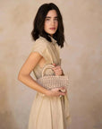 Profil d'une femme avec une robe chemise femme beige midi ceinturée, tenant un petit sac en paille, illustrant le style chic et décontracté.