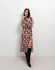 Femme en robe chemise longue imprimée bordeaux avec une coupe fluide, ajoutant une ceinture pour structurer sa silhouette.