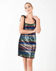 Femme en pose avec une robe courte à paillettes multicolores, élégante et chic pour soirées festives, affichant un design moderne.