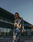 Femme portant une robe satin longue manche longue imprimée aquarelle, se tenant devant un bâtiment moderne, mettant en évidence l'élégance artistique et chic de la robe.