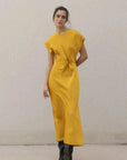 Robe De Soirée Jaune Satinée Élégante Avec Nœud À La Taille - Chic Et Fluide, modèle tourné légèrement en robe de soirée jaune, mettant en valeur le nœud à la taille.