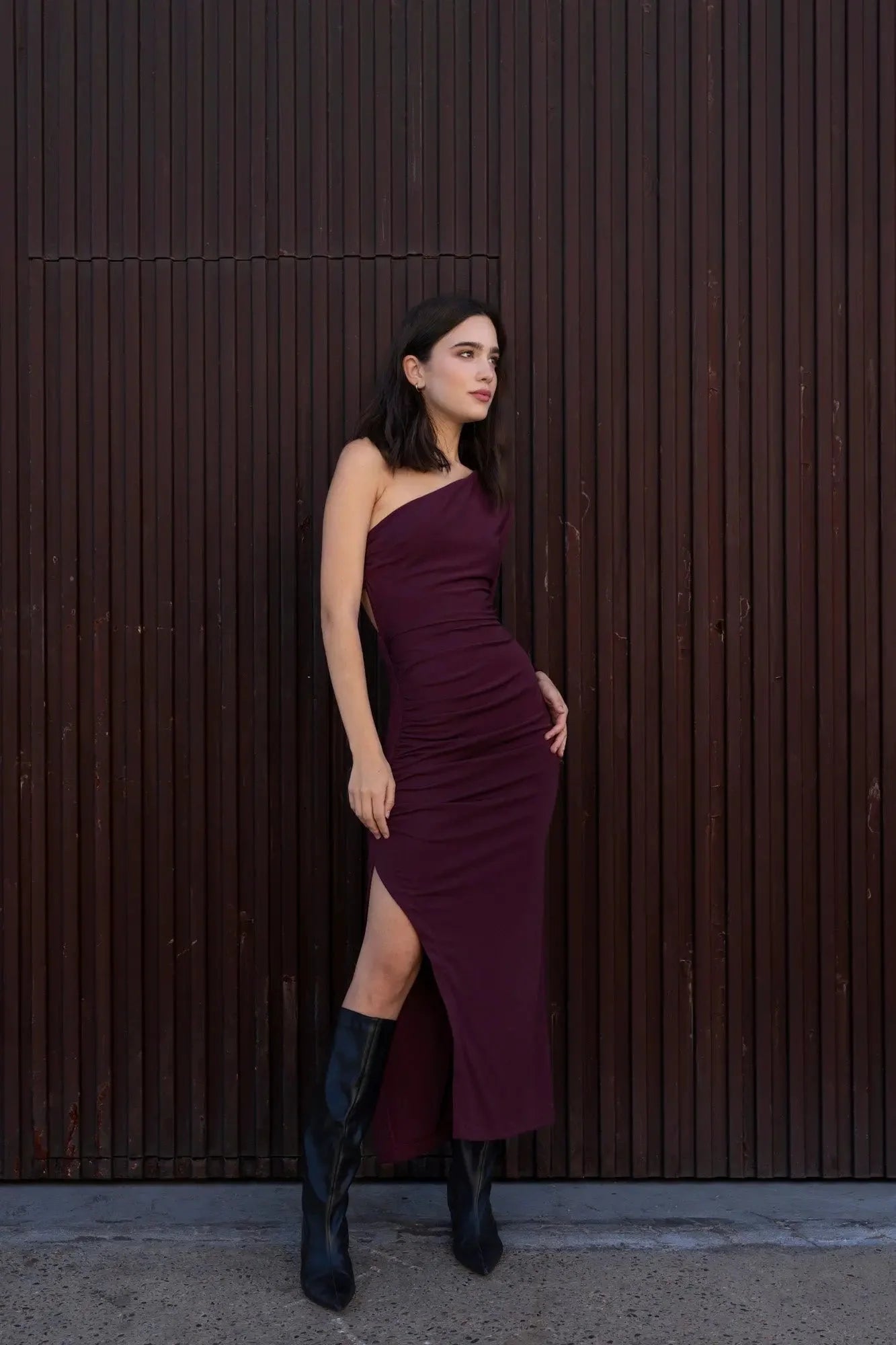 Robe longue asymétrique à manche unique avec slit, portée avec des bottes noires