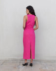 Femme vue de dos dans une robe fuchsia longue chic en lin, sans manches, encolure froncée, style minimaliste, révélant une fente.