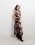 Vue latérale d'un modèle dans une robe tie dye longue satinée noir et rose, mettant en valeur son élégance.