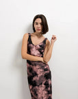 Modèle portant une robe tie dye longue satinée noir et rose, imprimé effet nuage, col en V, bretelles larges.