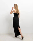 Vue arrière d'une femme portant une jupe midi noire, montrant la fente latérale qui ajoute une touche d'élégance.