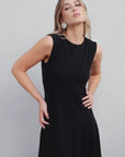Robe Longue Noire Élégante Sans Manches - Coupe Midi, Ourlet Festonné, Col Rond, portée par un modèle féminin, montrant un look élégant et simple.