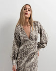 Femme portant une robe midi imprimé python à col cache-cœur, mettant en avant le motif reptile tendance, parfaite pour un look sauvage et sophistiqué. Idéale pour les amateurs de mode en quête d'une robe animal.