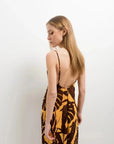 Détail d'une femme portant une robe imprimé tropical midi floral marron et jaune vue de dos, mettant en avant son design élégant.