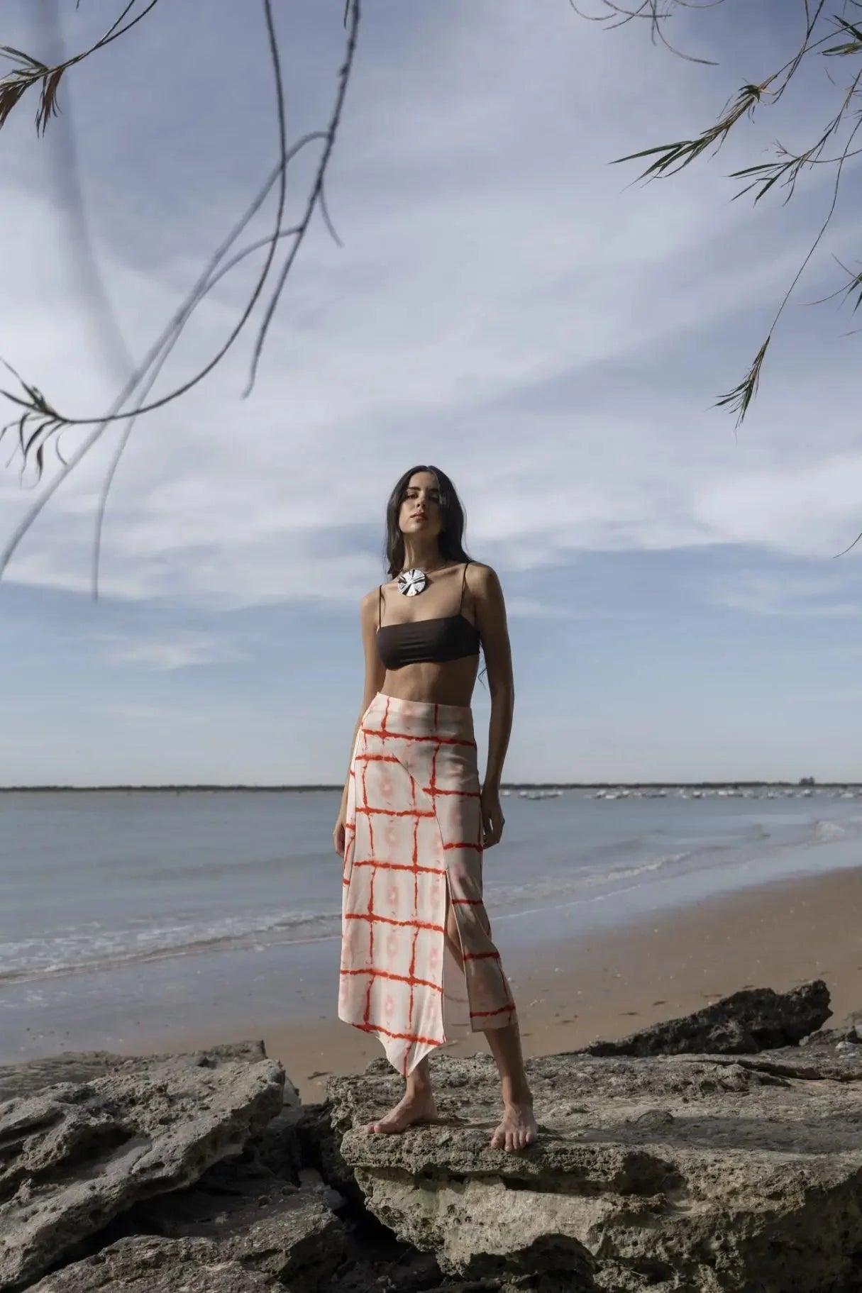 Femme portant une jupe midi imprimée asymétrique à rayures rouges et une bralette foncée