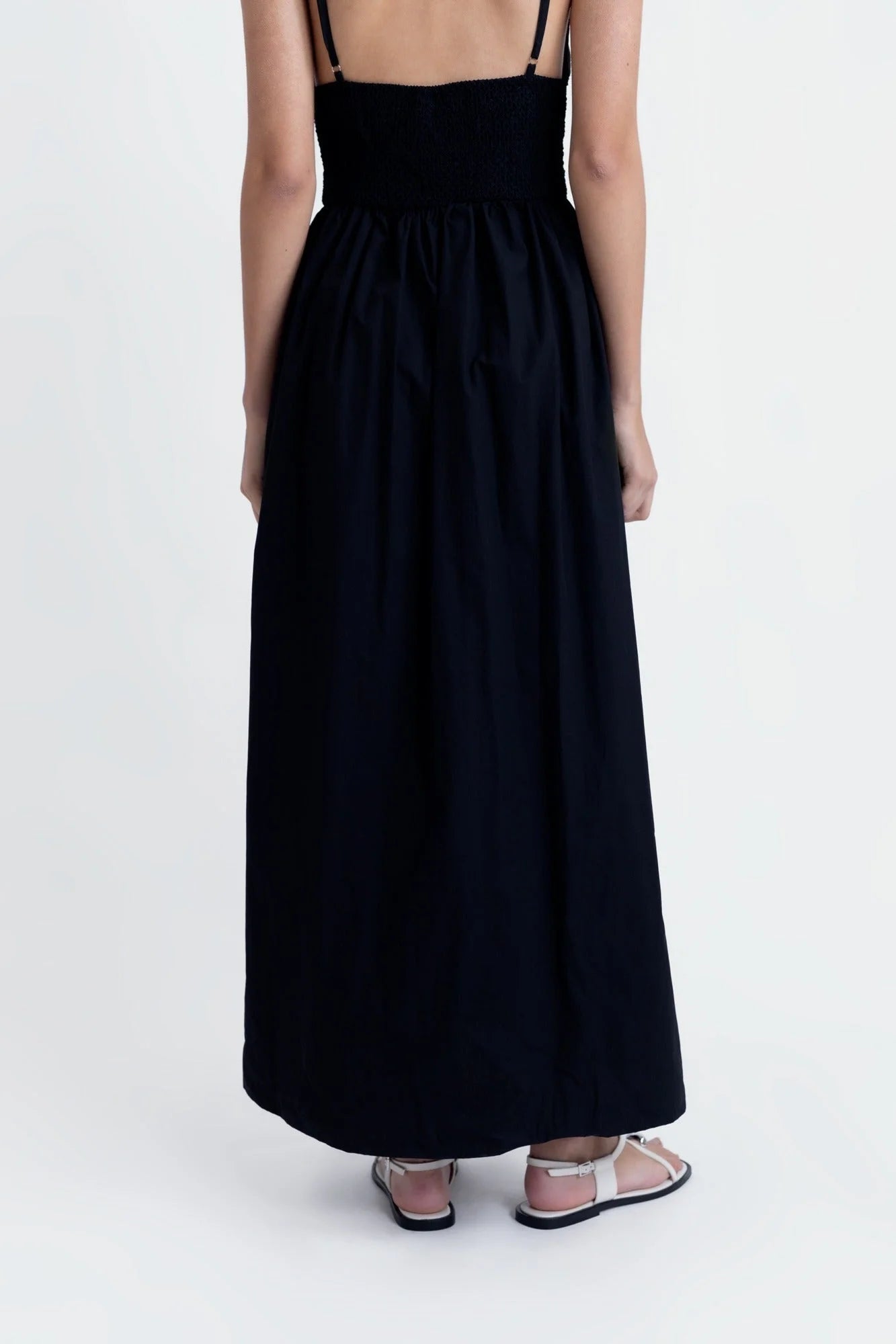 Robe midi noire sans manches avec buste plissé et sandales plates, élégance estivale