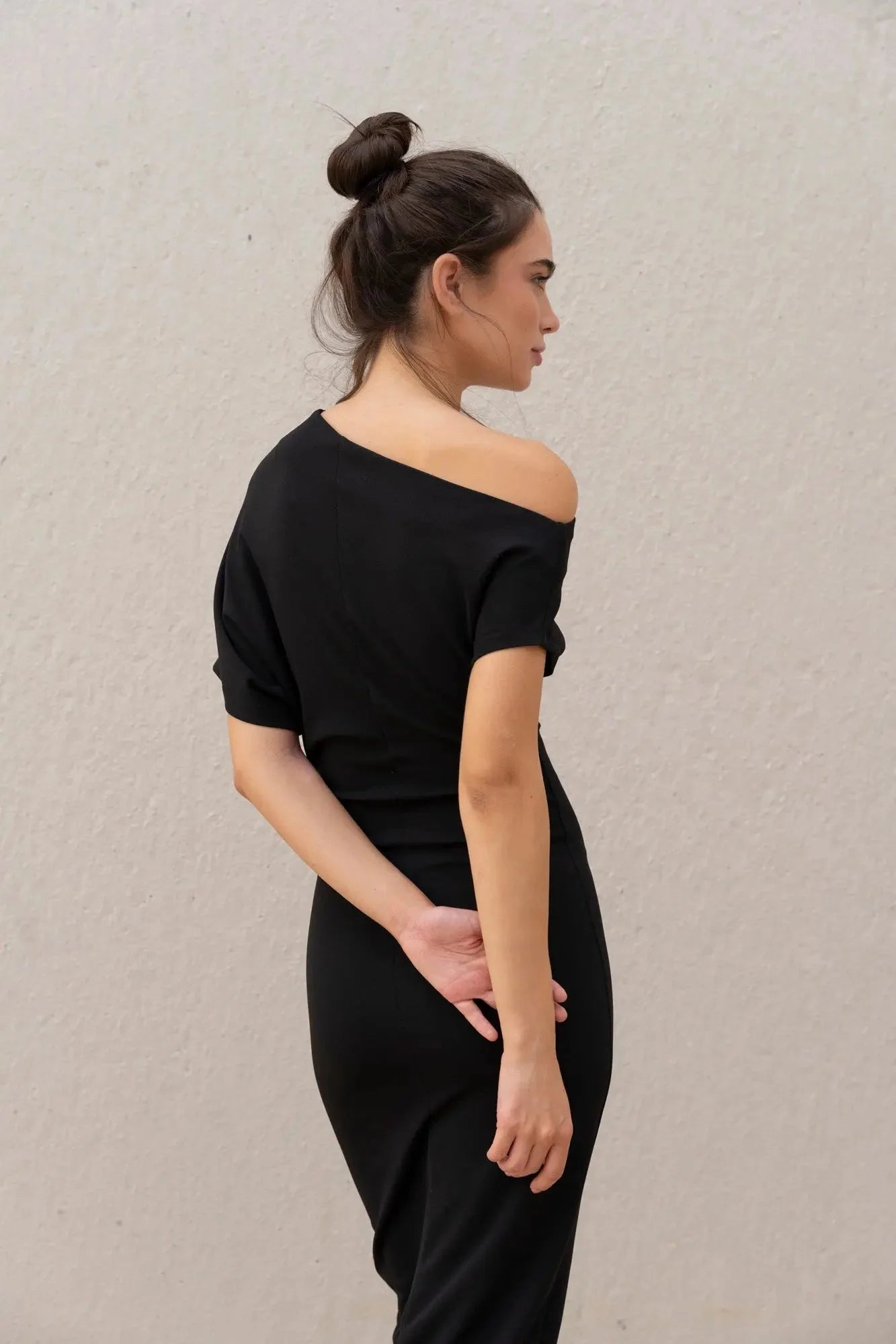 Femme portant une robe noire asymétrique épaule dénudée élégante et sophistiquée