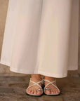 Zoom sur les sandales portées avec une robe longue blanche chic, montrant comment l'élégance se marie avec le confort.