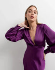 Modèle portant une robe midi satinée violette à manches longues, idéale pour une robe soirée en satin, mettant en avant une élégance moderne.