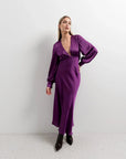 Femme posant en robe midi satinée violette à manches longues, parfait pour une robe soirée en satin, combinant confort et sophistication.