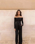 Body Femme Noir Manche Longue À Épaules Dénudées associé à un pantalon élégant, parfaite pièce pour des occasions variées.
