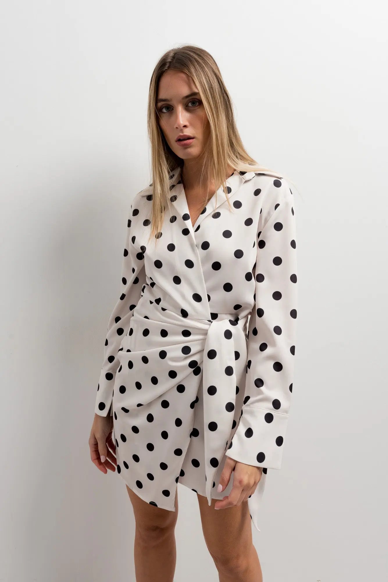 Robe portefeuille à pois noirs et blancs nouée à la taille portée par une femme