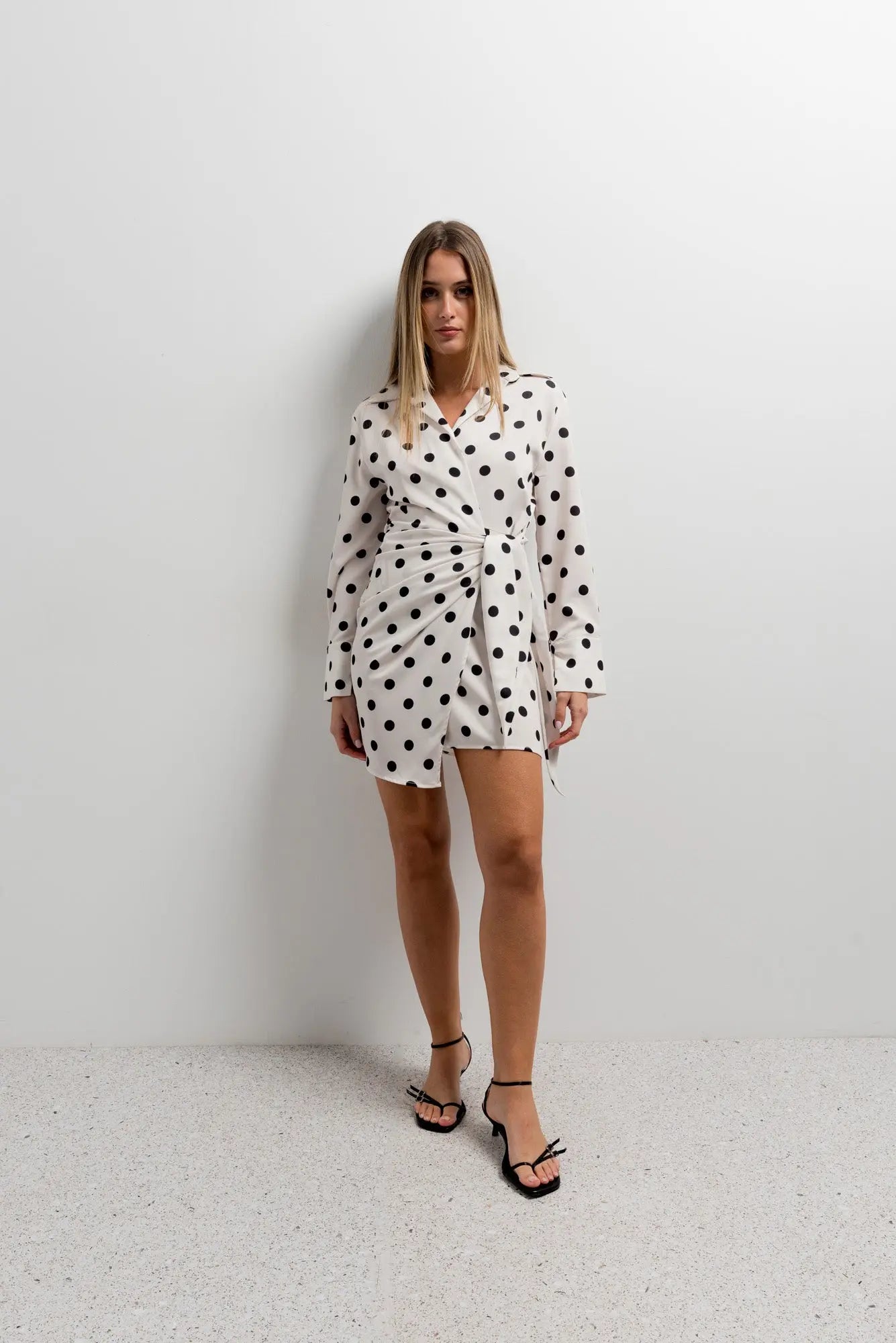 Robe portefeuille à pois noirs et blancs nouée à la taille portée par une femme