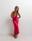 Femme en robe dos nu satin rouge éclatant, affichant un look élégant et décontracté avec décolleté drapé.