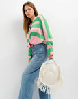 Femme avec sac panier rond en macramé à franges, veste à rayures rose et vert