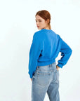 Femme portant un sweat-shirt court bleu ceinturé pour un look plus chic