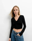 Modèle féminin dans un T-Shirt Crop Top Manche Longue Avec Noeud Élégant Pour Femme, décontracté et élégant, devant un fond épuré.