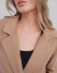 Zoom sur le col et le tissu d'un blazer fluide camel porté par une femme.