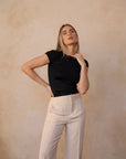 Modèle féminin adoptant une pose confiante dans un tailleur crème, soulignant le style moderne du pantalon pince femme.