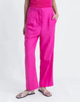 Détail d'un pantalon femme mode lin rose fuchsia taille haute fluide, porté avec des sandales modernes.