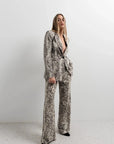Modèle dans un tailleur pantalon palazzo imprimé animal serpent, montrant une élégance moderne et tendance. Idéal pour un look pantalon palazzo femme chic.