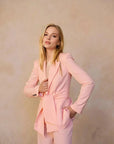 Pantalon rose femme ceinturé pour toutes occasions, portrait d'une femme en blazer montrant un style sophistiqué.