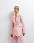Pantalon rose femme ceinturé pour toutes occasions, une femme en pose élégante avec un blazer rose, idéale pour un look tendance.