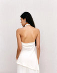 Vue arrière du haut dos nu femme chic Ivoire à col montant halter, mettant en avant le dos dénudé et la coupe asymétrique, mannequin avec des accessoires modernes.