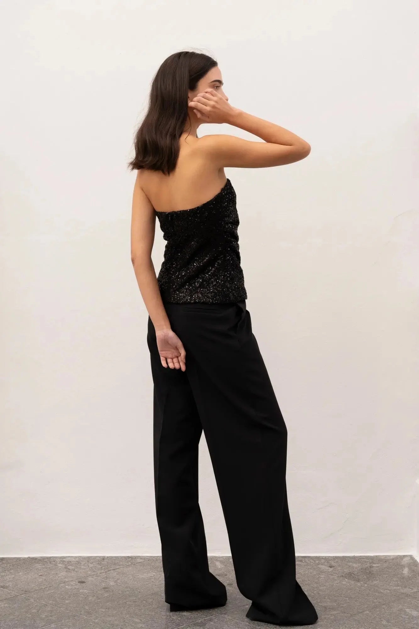 Femme portant un top bandeau femme noir élégant en sequins et pantalon large noir