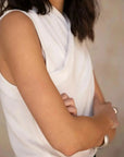 Détail du Top Croisé Devant Blanc Chic, avec un tissu fluide et sans manches, mettant en valeur la coupe.