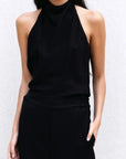 Détail du top halter noir et pantalon assorti, mettant en valeur la coupe fluide et le col montant. Un incontournable pour un haut long femme chic.