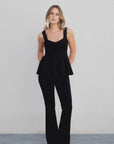 Modèle en top peplum femme noir élastique avec un pantalon noir, parfait pour un look élégant et chic.