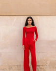 Image d’une femme portant un body rouge à épaules dénudées manches longues