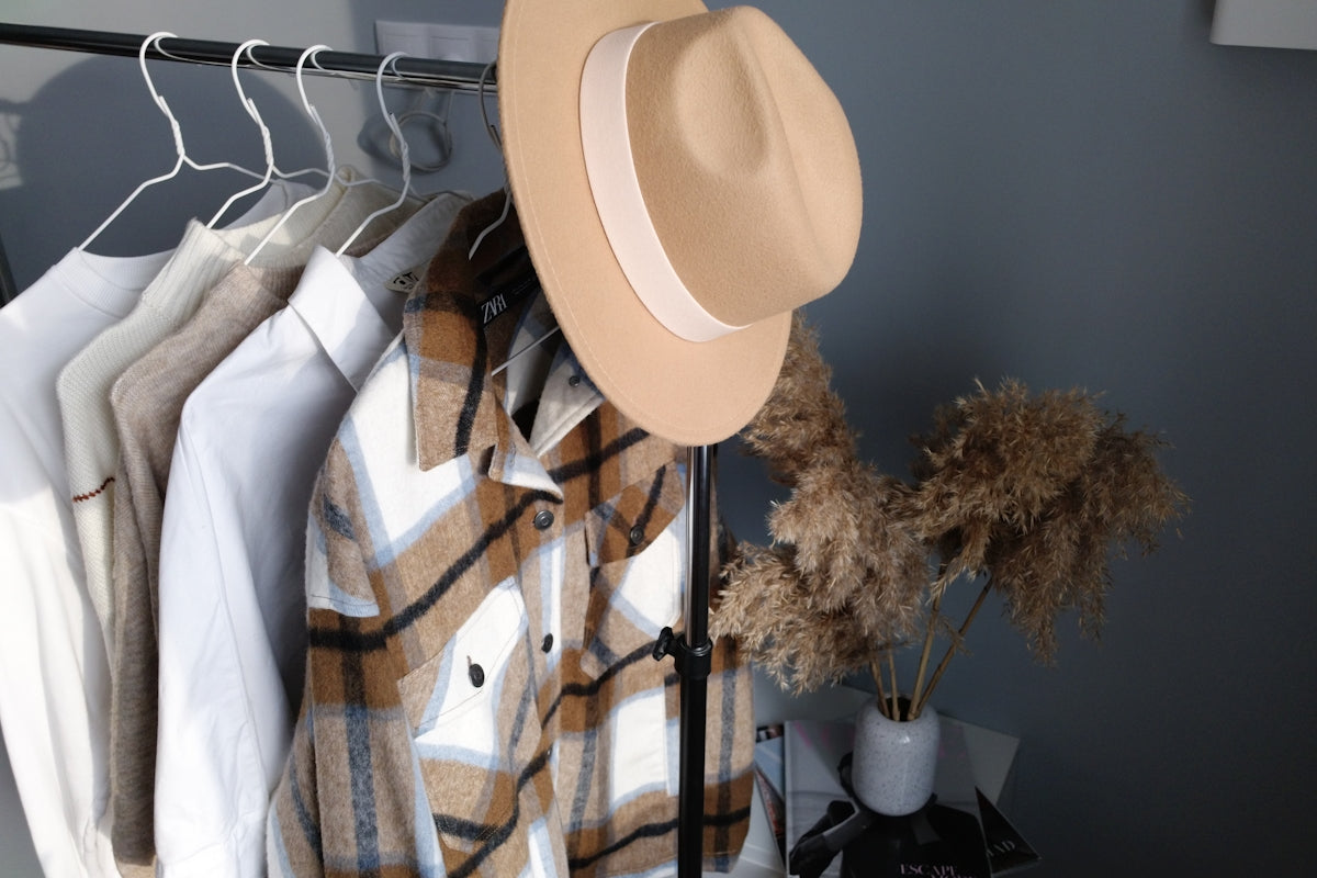white fedora hat hanged on black metal rack