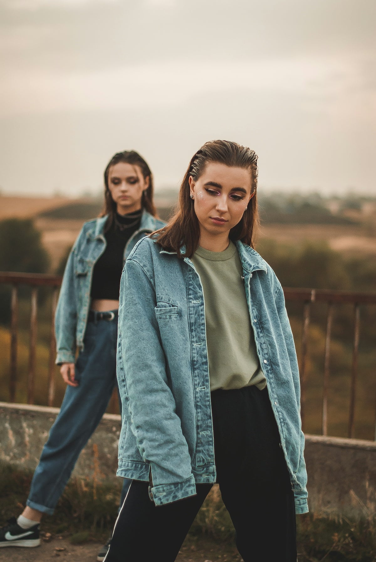 woman in blue denim jacket standing near brown wooden fence during daytime