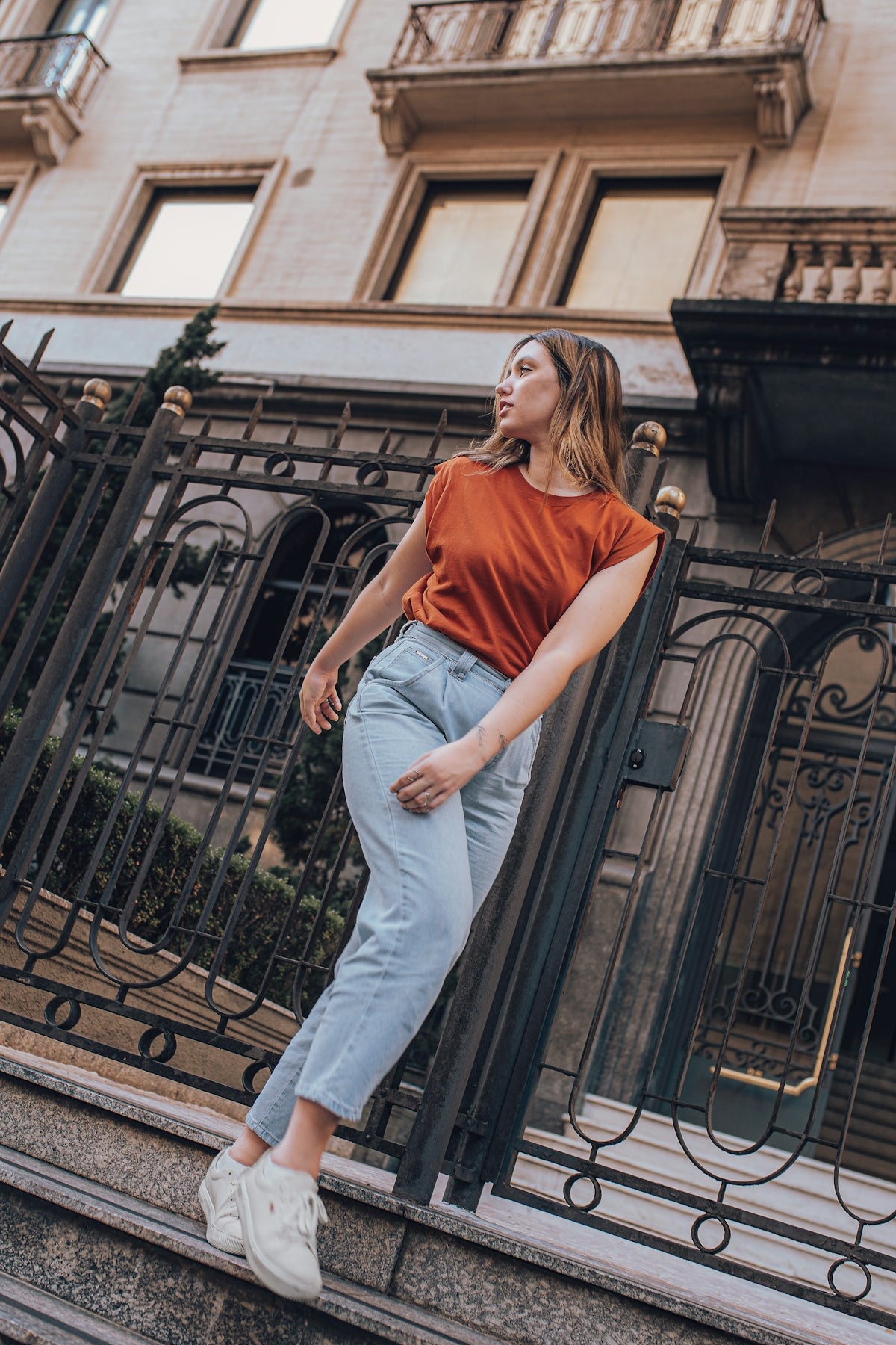 woman in red sleeveless shirt and white pants standing on brown concrete stairs