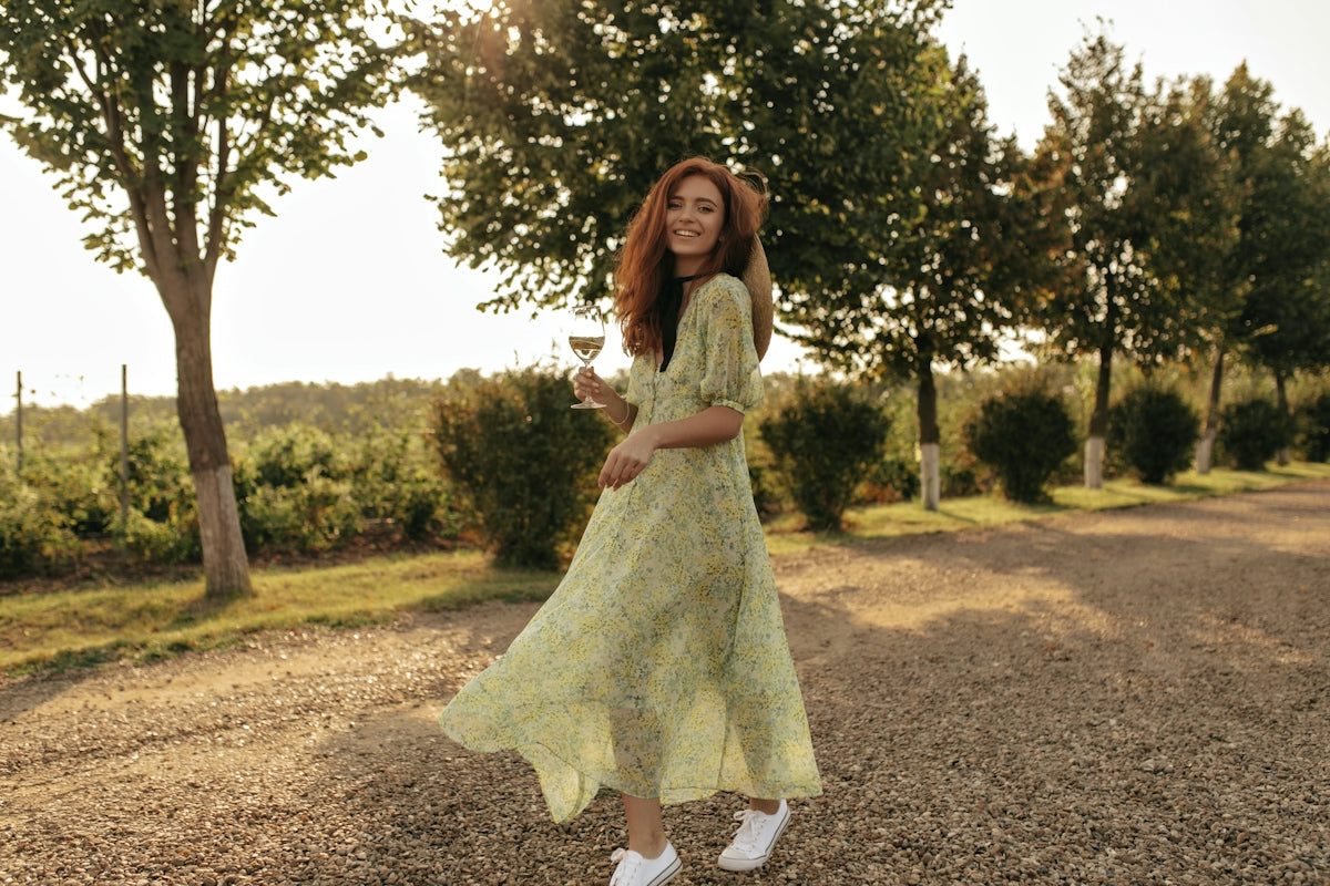 a woman in a yellow dress holding a glass of wine