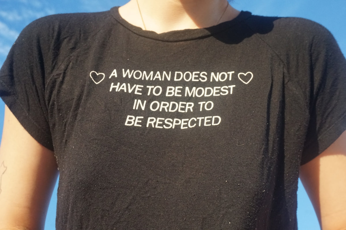 A woman wearing a t - shirt that says a woman does not have to be