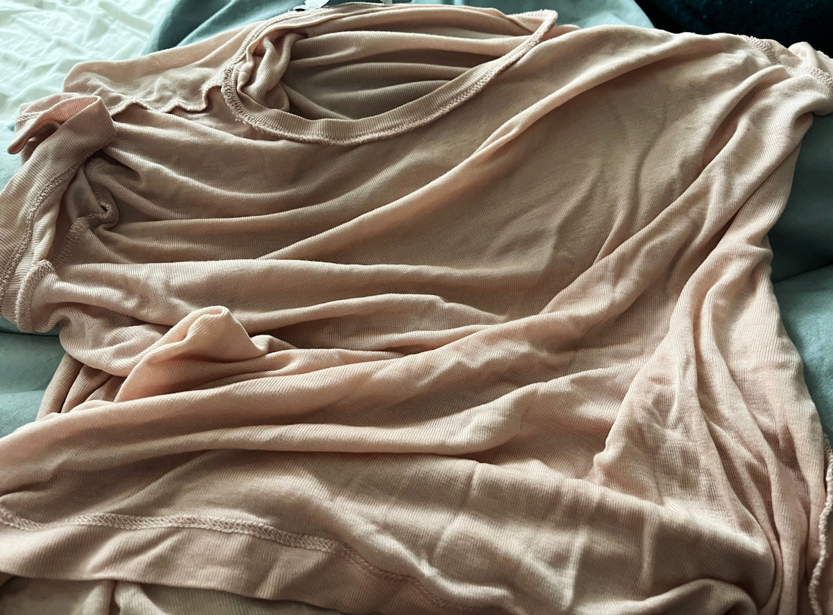 A person laying on a bed covered in a blanket