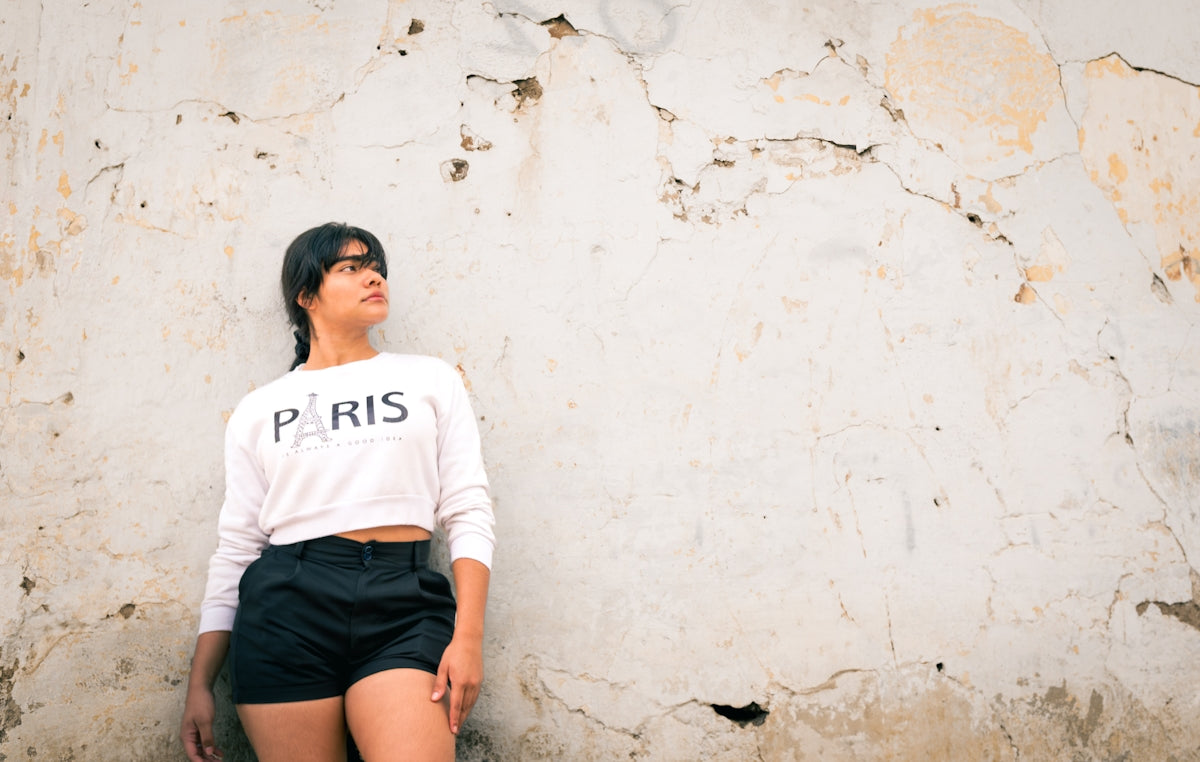 A woman leaning against a wall with her legs crossed