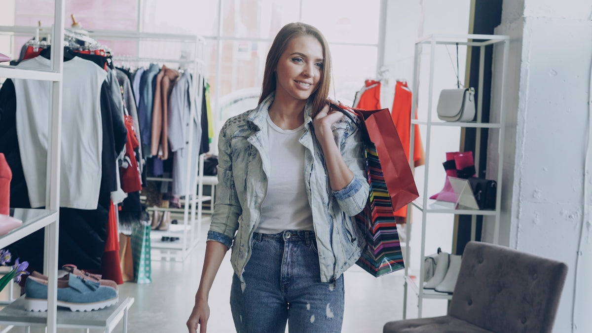 Happy woman walks out of a shop with shopping bags.