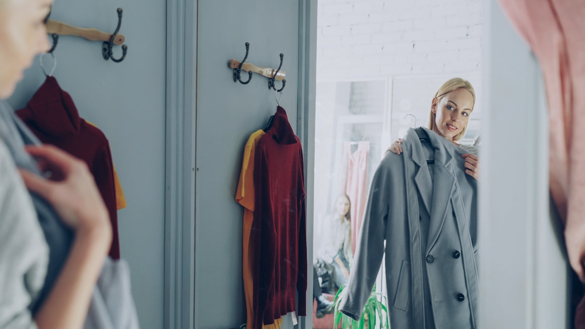 Woman trying on a coat in a mirror.