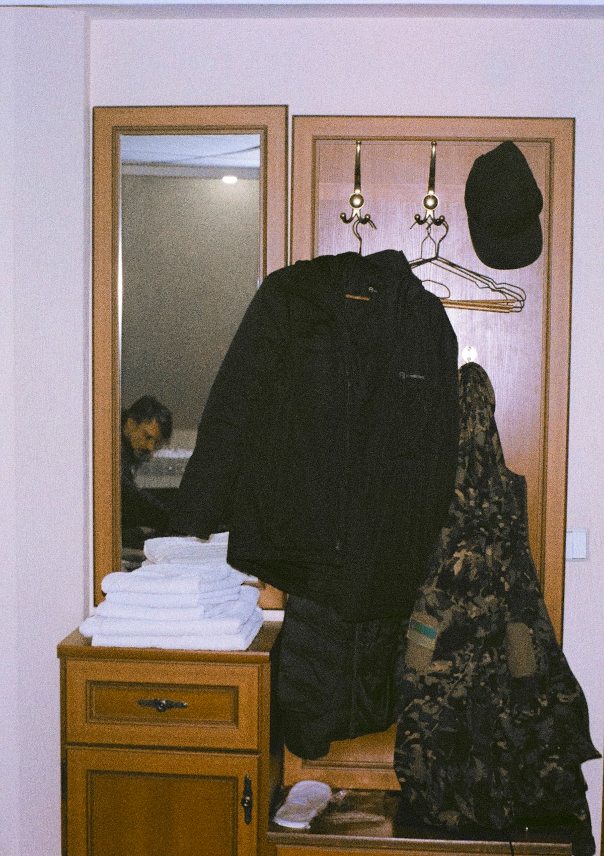 Coat, cap, and towels on entryway furniture.